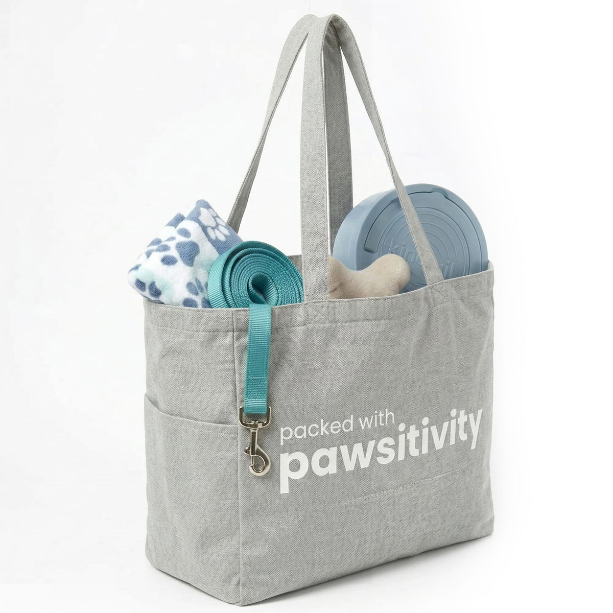 Large beige tote bag with "Pawsitivity" printed on the front, featuring handles and a spacious interior, by KindTail.